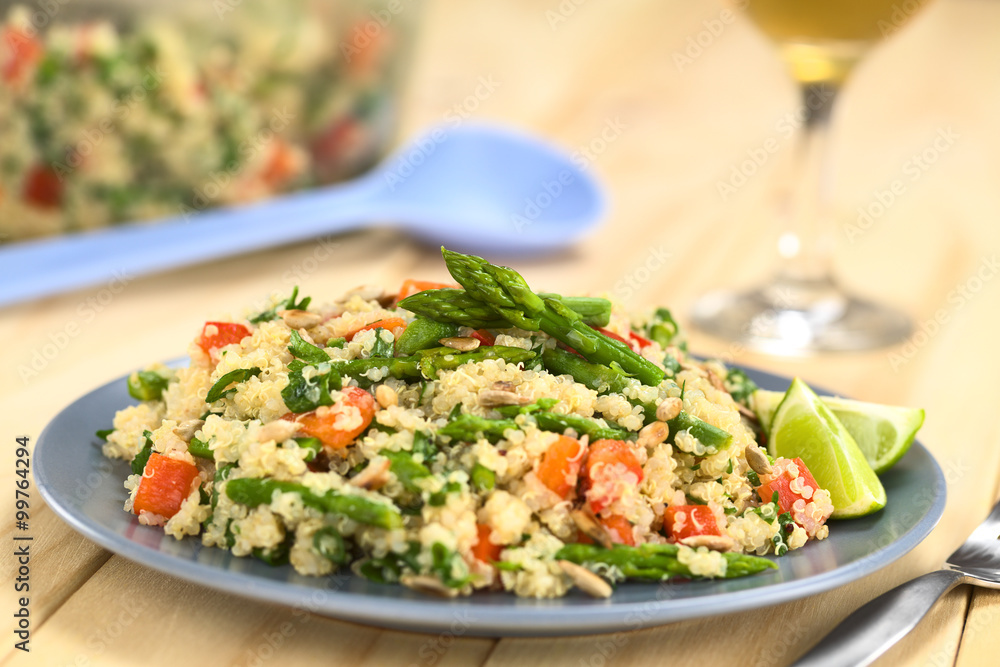 Vegetarian quinoa dish with green asparagus and red bell pepper, sprinkled with parsley and roasted sunflower seeds, lime wedges on the side (Selective Focus, Focus on the asparagus heads on the dish) Vegetarian quinoa dish with green asparagus and red bell pepper, sprinkled with parsley and roasted sunflower seeds, lime wedges on the side (Selective Focus, Focus on the asparagus heads on the dish)