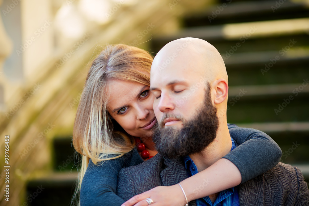One beautiful stylish couple of young woman and senior man with long black beard sitting embracing close to each other outdoor in autumn street on stairs sunny day, horizontal picture One beautiful stylish couple of young woman and senior man with long black beard sitting embracing close to each other outdoor in autumn street on stairs sunny day, horizontal picture