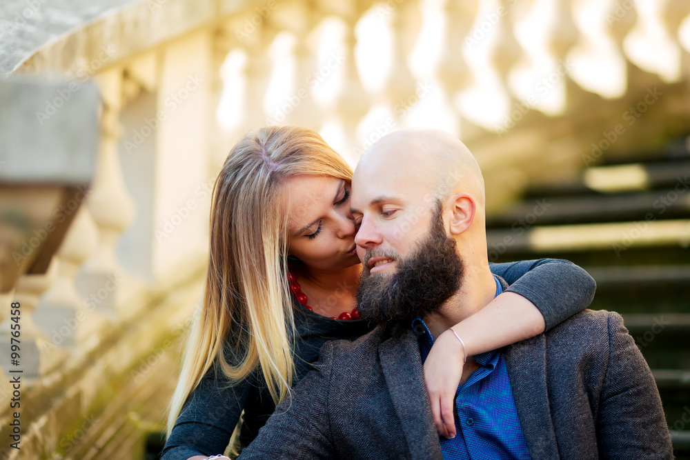 Young couple, stylishly dressed, sitting on the steps, against a historic building Young couple, stylishly dressed, sitting on the steps, against a historic building