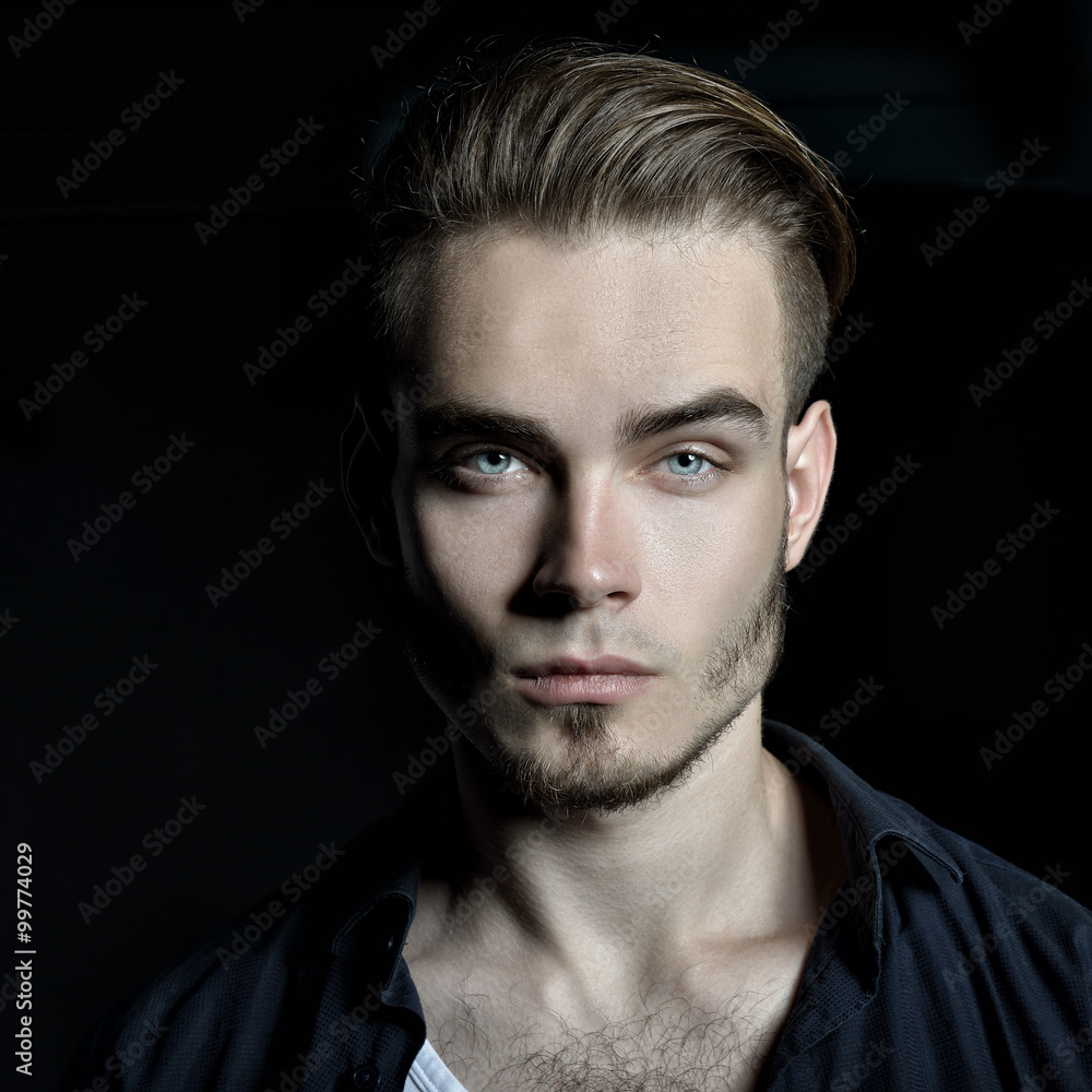Portrait of young man over black background, image toned. Portrait of young man over black background, image toned.