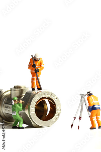 Miniature construction workers plumbing valve / Isolated miniature scale model construction workers with a plumbing valve
