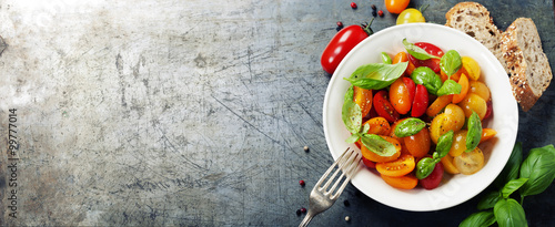 Fresh tomatoes with basil leaves in a bowl