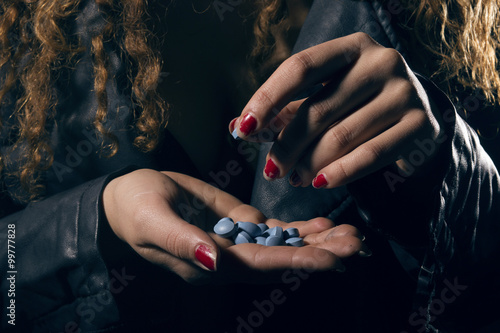 Drug abuse. Woman with pills in hand taking one. photo