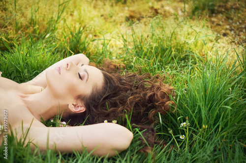 Pretty brunette woman lying on the fresh lawn