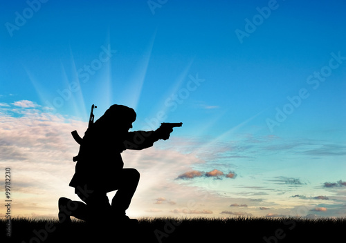 Silhouette of man with gun against cloudy sky during sunset