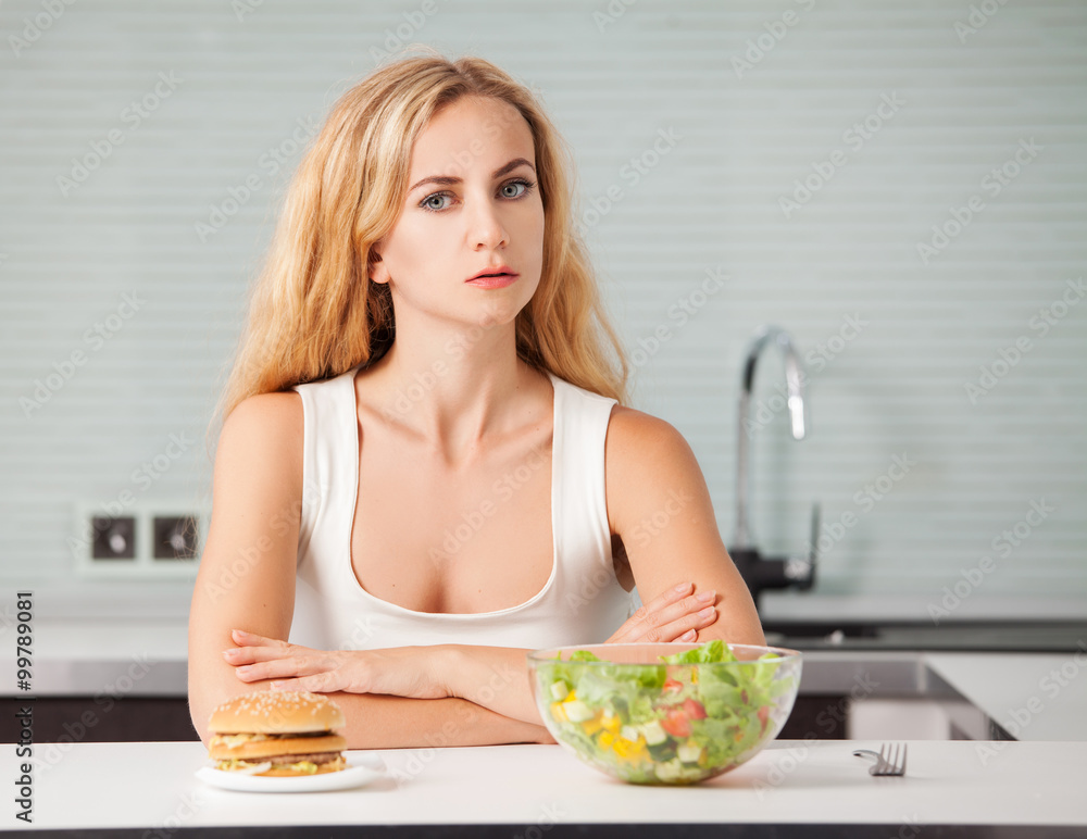 Woman chooses between a healthy and unhealthy food Woman chooses between a healthy and unhealthy food