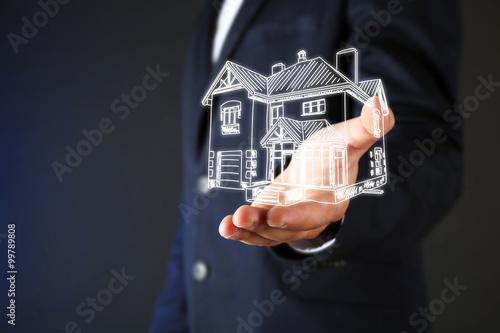 Real estate offer. Businessman holds an artificial model of the house