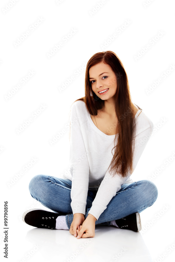 Smiling young woman sitting on a floor with legs crossed Smiling young woman sitting on a floor with legs crossed