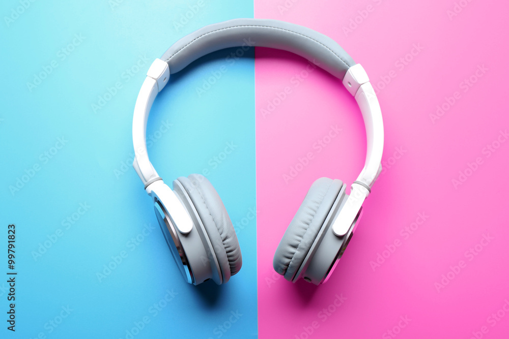 Wireless white and grey headphones on pink-blue background Wireless white and grey headphones on pink-blue background