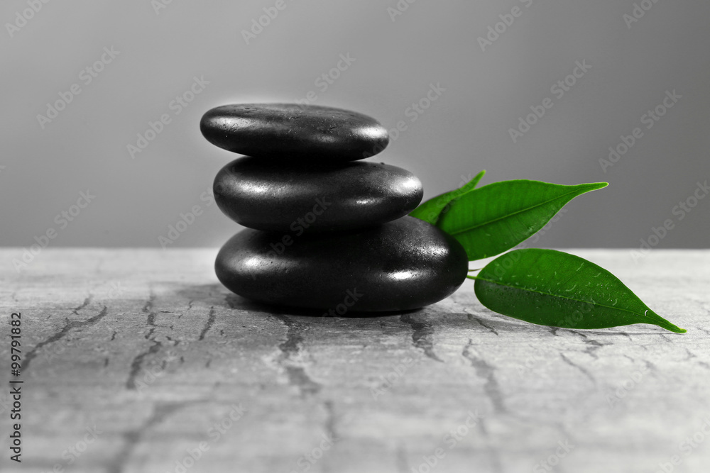 Fototapeta premium Pile of pebbles with leaf on the table against grey background