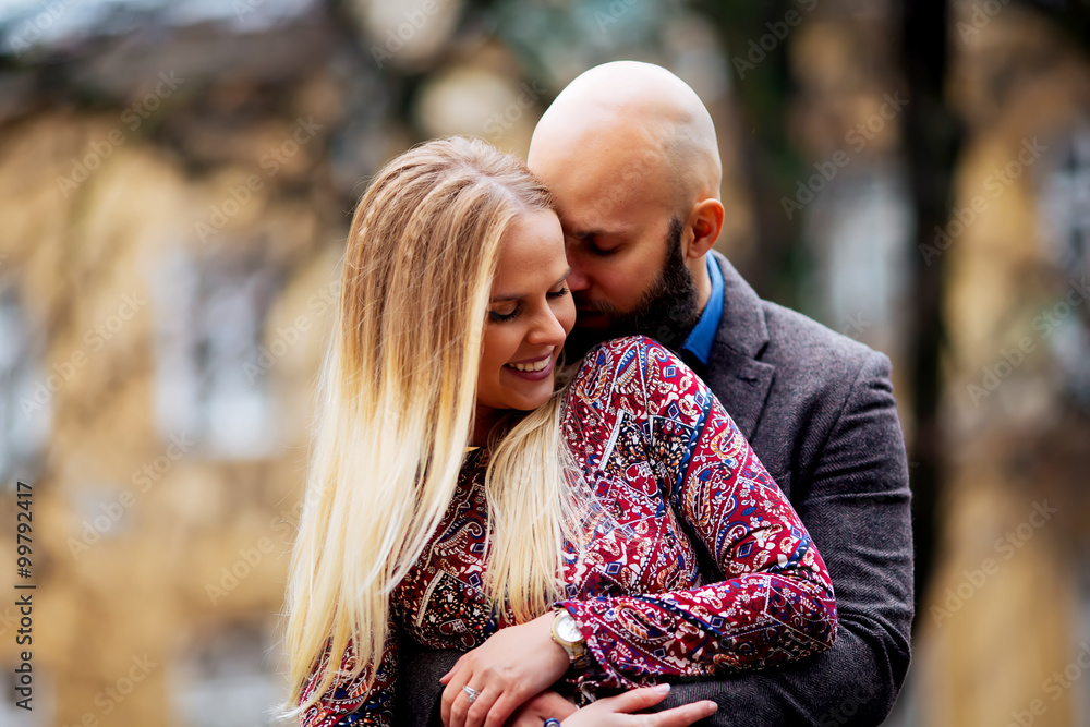 Fototapeta premium Young couple in love, hugging on the street. Selective focus. bald guy with a beard