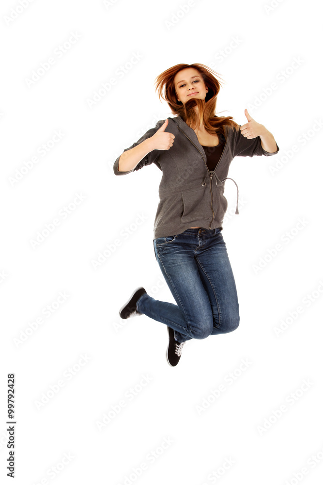 Teenage woman jumping showing thumbs up Teenage woman jumping showing thumbs up