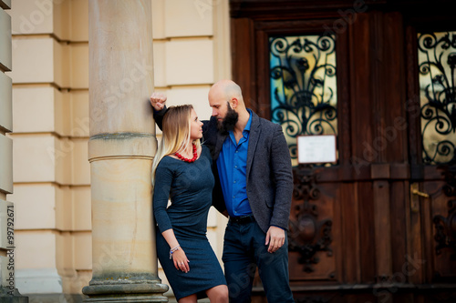 happy couple in love with each other,One beautiful stylish couple of young woman and senior man with long black beard embracing close to each other outdoor in autumn street on stairs sunny day