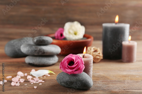 Beautiful composition of aroma candle with pebbles and flower on wooden background