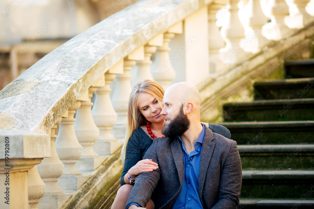 Obraz premium happy couple in love with each other,One beautiful stylish couple of young woman and senior man with long black beard embracing close to each other outdoor in autumn street on stairs sunny day