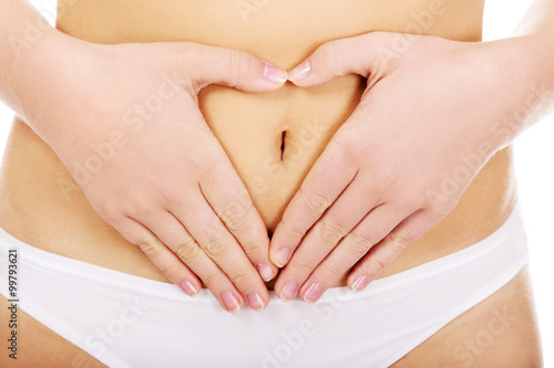 Young woman in white panties making heart shape on her belly