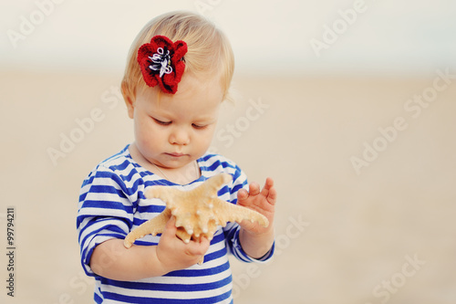 Маленькая девочка держит ракушку в руках