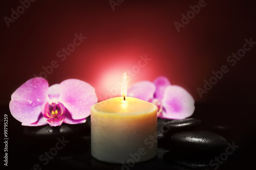 Composition of orchid, pebbles and candle on dark background