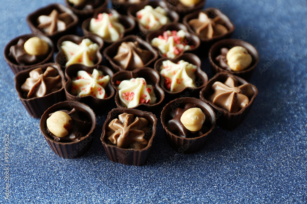 Delicious chocolate candies on blue background, close up Delicious chocolate candies on blue background, close up