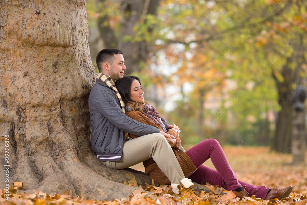 Young couple sitting under the tree in nature Young couple sitting under the tree in nature