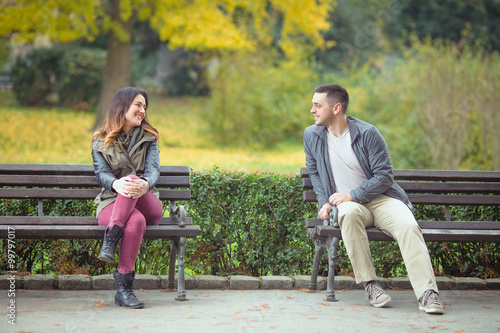Fotografija Two young people sitting on benches in a park and talking