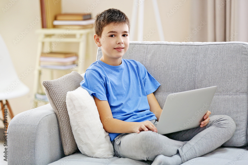 Boy with laptop sitting on a sofa at home Boy with laptop sitting on a sofa at home