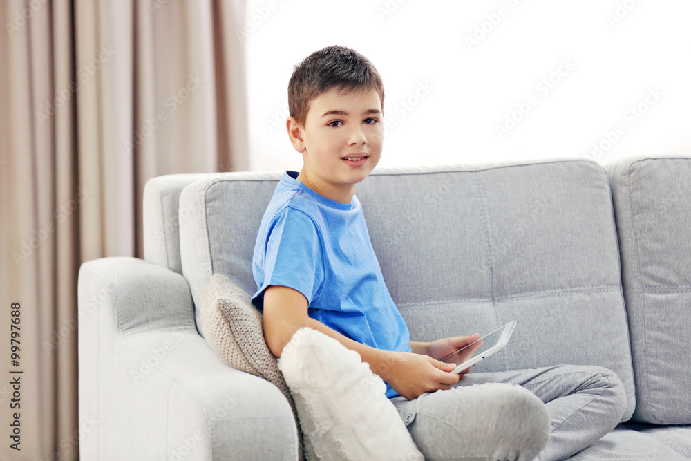 Boy with tablet sitting on a sofa at home Boy with tablet sitting on a sofa at home