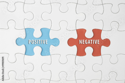 Jigsaw puzzle on color paper background with a word POSITIVE and NEGATIVE