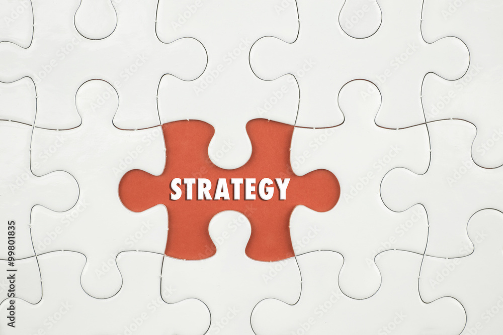 Jigsaw puzzle on color paper background with a word STRATEGY Jigsaw puzzle on color paper background with a word STRATEGY