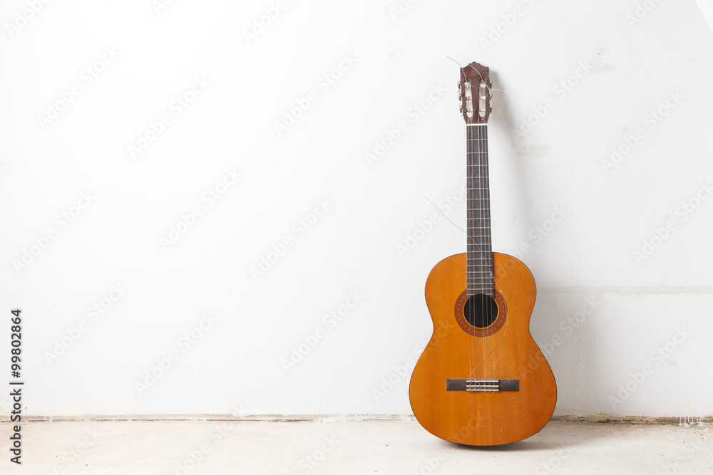 Naklejka premium Old classical acoustic guitar on white wall background