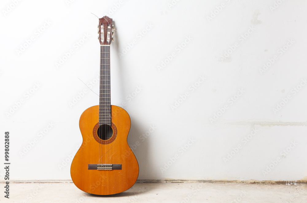 Naklejka premium Old classical acoustic guitar on white wall background