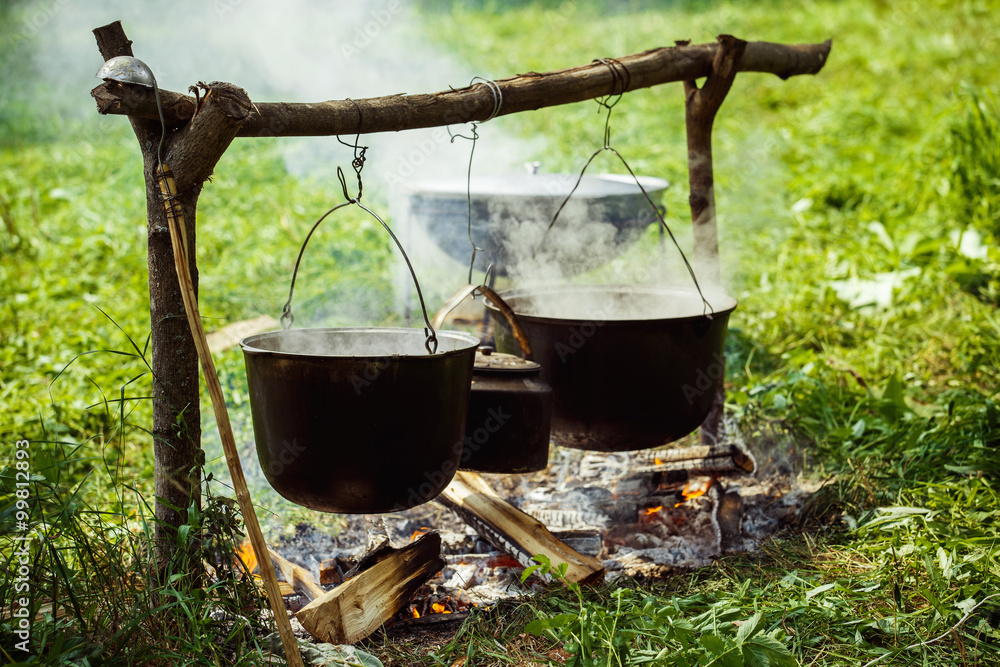 A group of cauldrons and kettle are hanged upon fire A group of cauldrons and kettle are hanged upon fire
