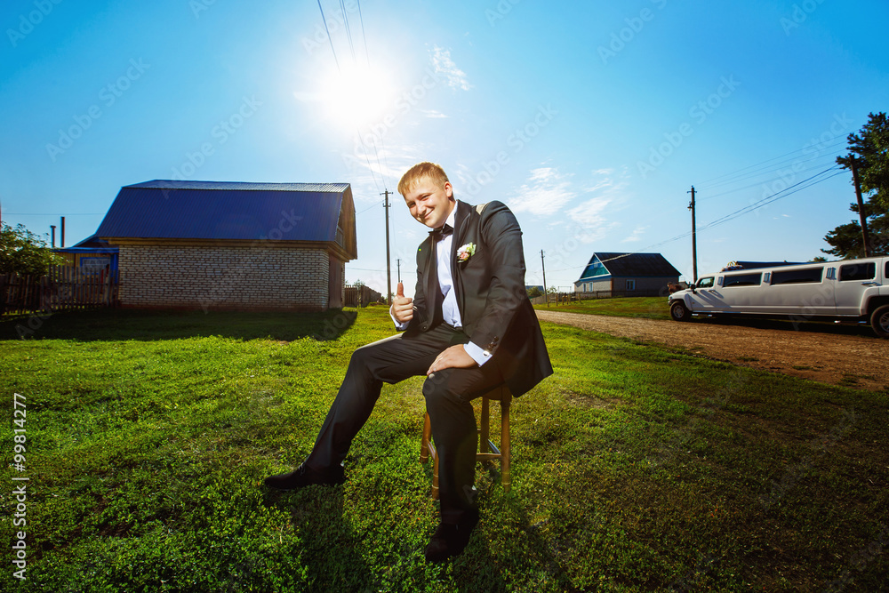 Portrait of happy handsome man in suit sitting on chair outdoors Portrait of happy handsome man in suit sitting on chair outdoors