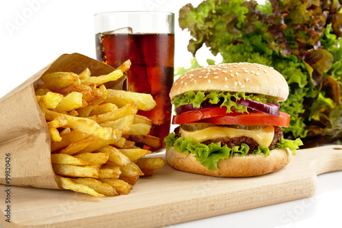 Cropped image of cheeseburger,french fries,glass of cola on wood