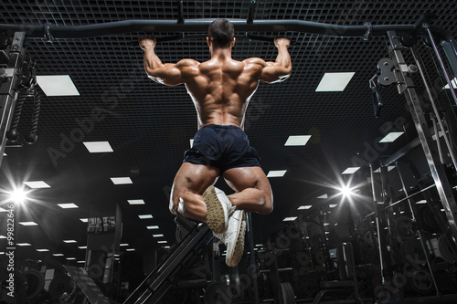 Athlete muscular fitness bodybuilder male model pulling up on horizontal bar