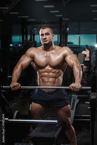 Muscular athletic bodybuilder fitness model posing after exercises