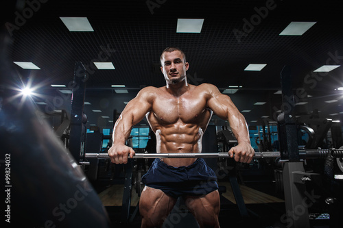 Muscular athletic bodybuilder fitness model posing after exercises 