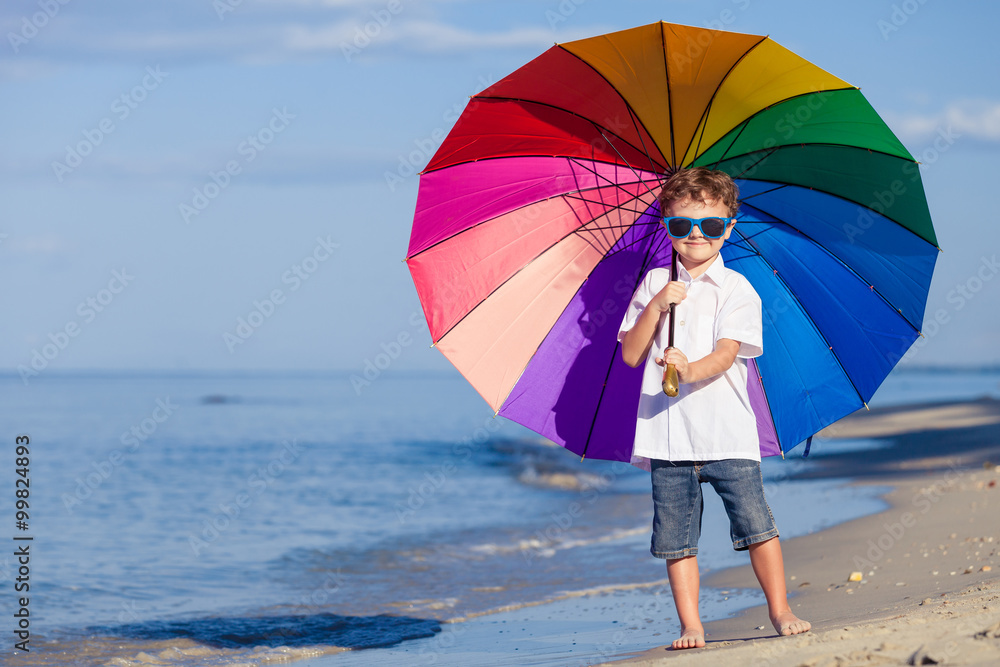 Little boy with umbrella standing on the beach