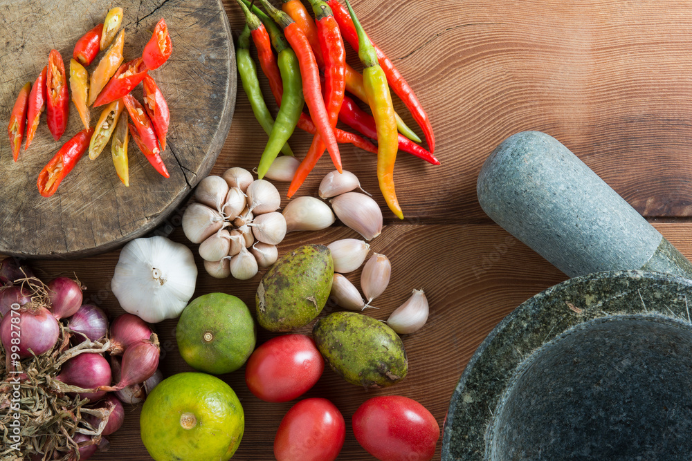 Thailand Food Ingredients: Tomatoes, peppers, garlic, shallots, lemon, olive with a mortar on a wooden floor. Thailand Food Ingredients: Tomatoes, peppers, garlic, shallots, lemon, olive with a mortar on a wooden floor.