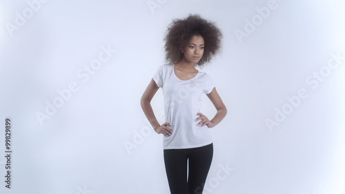 Young afro american woman in white t-shirt posing over white background.