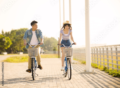 happy young couple riding on bicycle in city park
