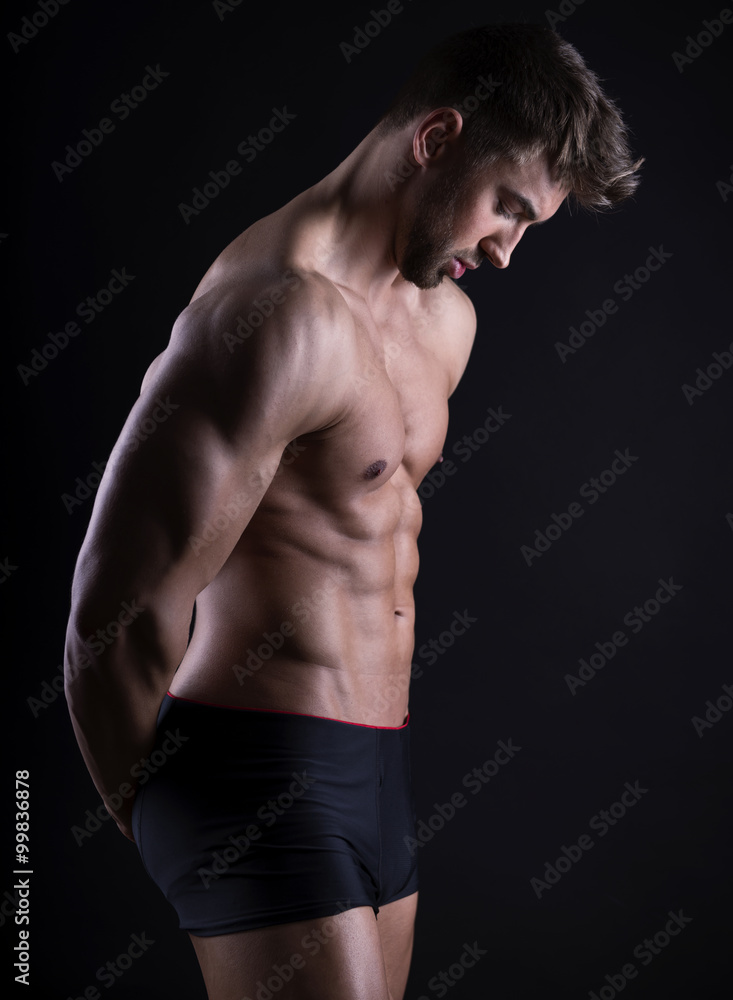 handsome young bodybuilder with toned body posing shirtless