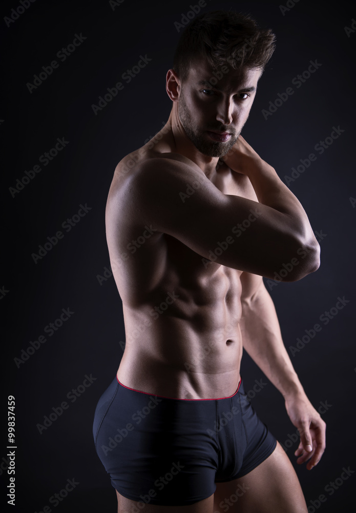 handsome young bodybuilder with toned body posing shirtless