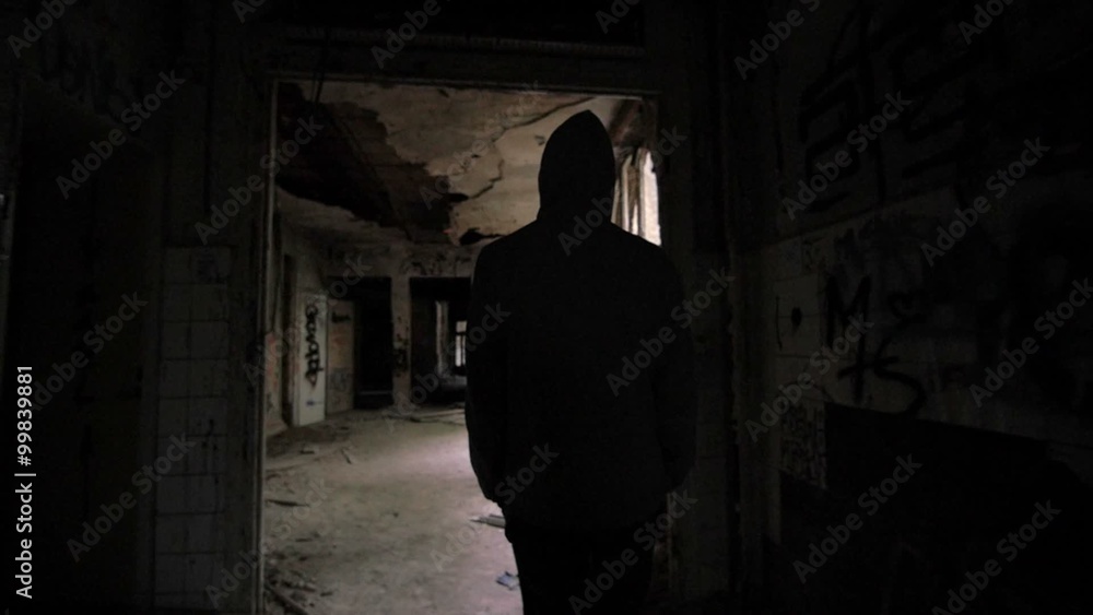 Slow motion of a guy with hood walking through abandoned building Slow motion of a guy with hood walking through abandoned building