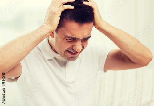 unhappy man suffering from head ache at home