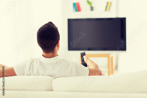 man watching tv and changing channels at home