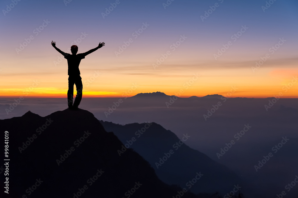 man on top of the mountain spread hand and looking to the sunrise
