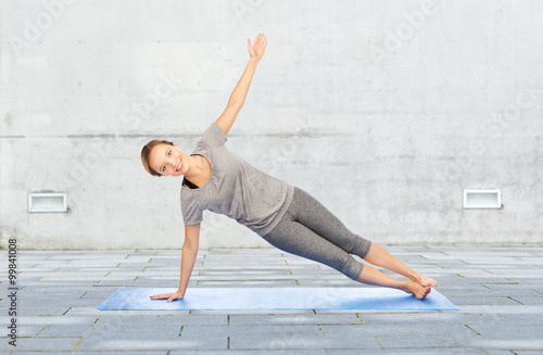 woman making yoga in side plank pose on mat