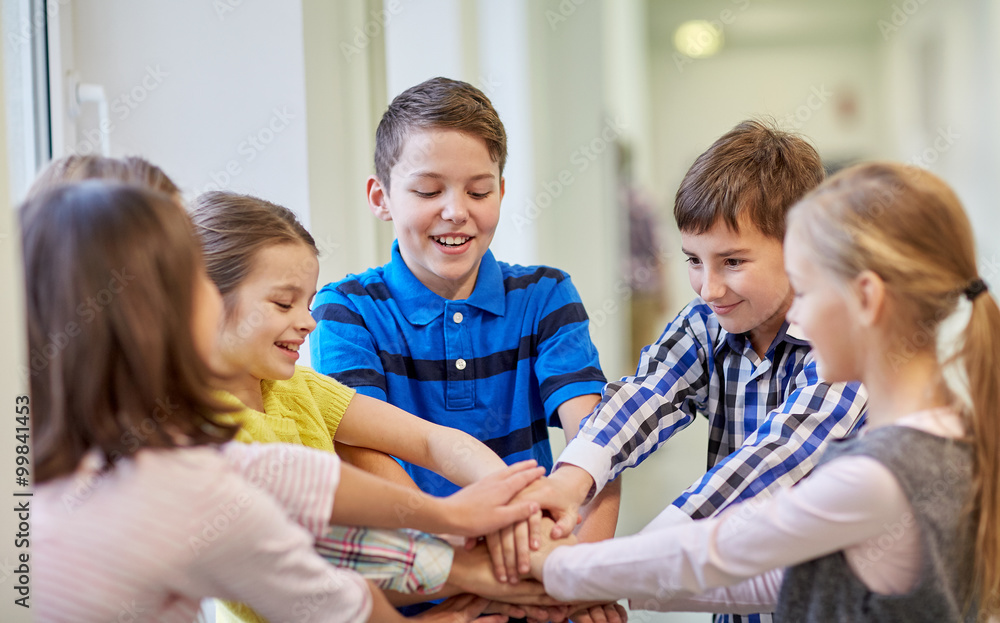 group of smiling school kids putting hands on top group of smiling school kids putting hands on top