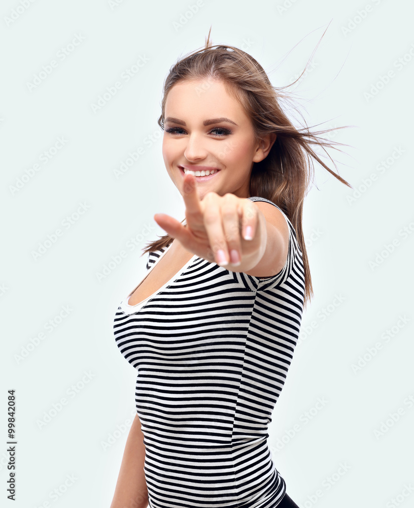Happy young woman with windblown hair pointing at you Happy young woman with windblown hair pointing at you